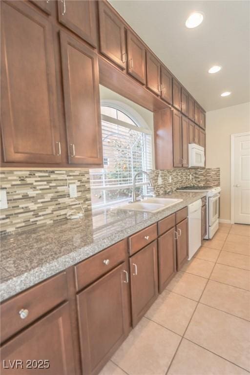 kitchen with white appliances, a sink, light countertops, backsplash, and light tile patterned flooring