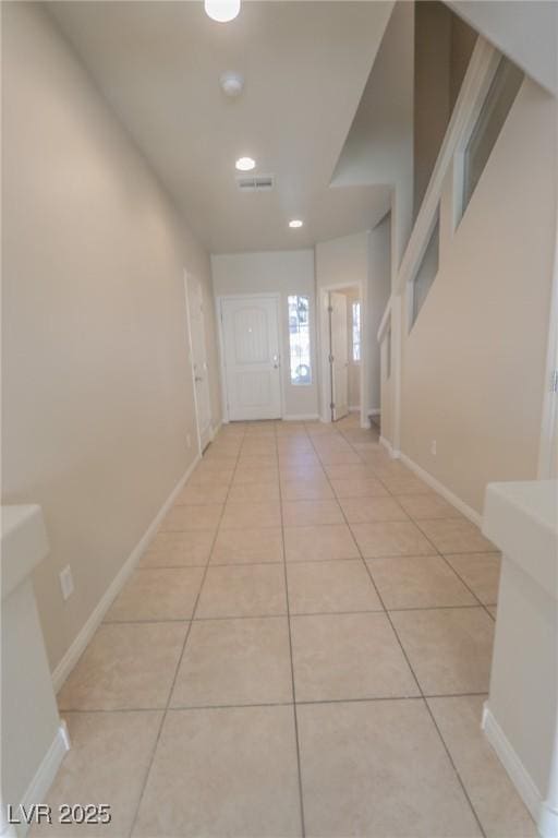 corridor with light tile patterned floors, stairs, visible vents, and baseboards