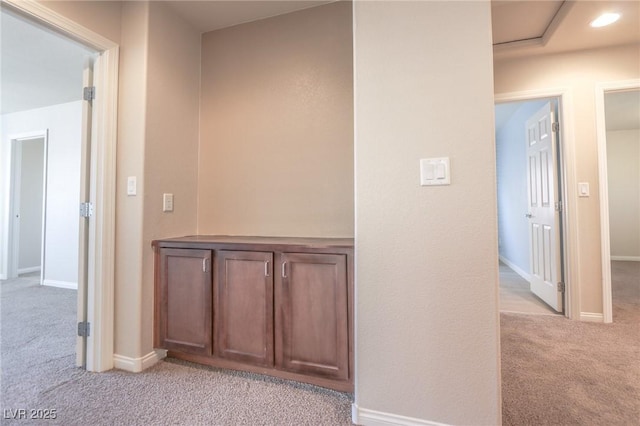 hall with recessed lighting, light colored carpet, and baseboards