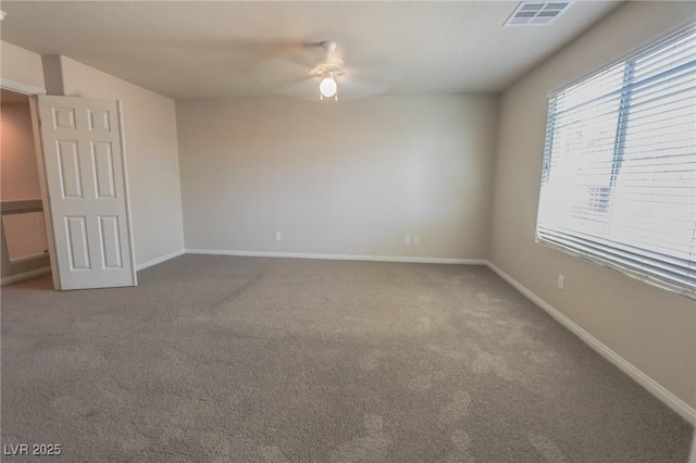 carpeted spare room with baseboards, visible vents, and a ceiling fan