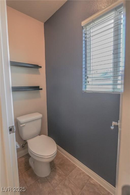 bathroom with toilet, tile patterned flooring, and baseboards