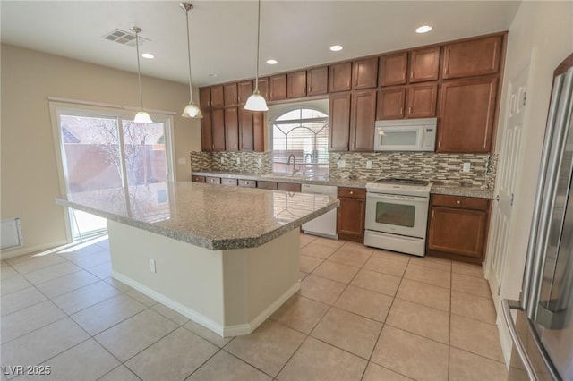 kitchen featuring white appliances, visible vents, brown cabinetry, and a center island