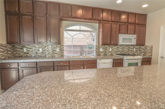 kitchen with white appliances, tasteful backsplash, light stone counters, a sink, and recessed lighting