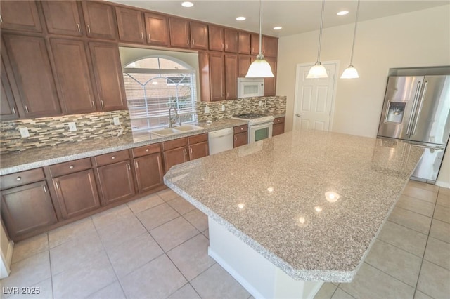 kitchen featuring a center island, white appliances, a sink, and hanging light fixtures