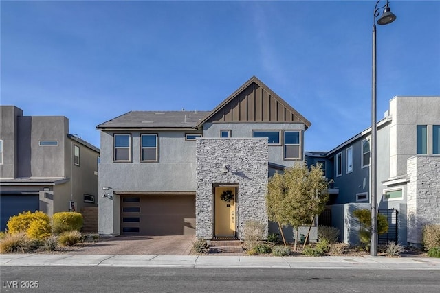 view of front of house with a garage, stone siding, decorative driveway, stucco siding, and board and batten siding