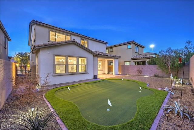 back of house with a fenced backyard, a tiled roof, and stucco siding