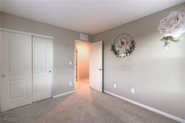 unfurnished bedroom with carpet floors, a closet, visible vents, and baseboards