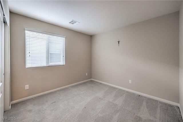 spare room with carpet, visible vents, and baseboards