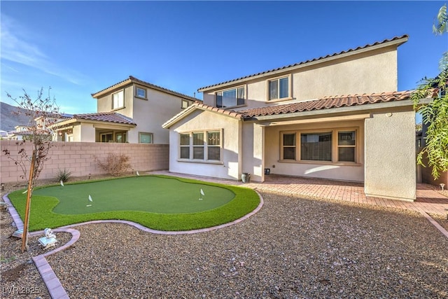 rear view of property featuring a fenced backyard, a patio, a tiled roof, and stucco siding