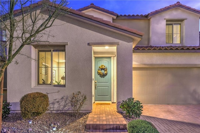 view of front facade with a tile roof, stucco siding, and decorative driveway