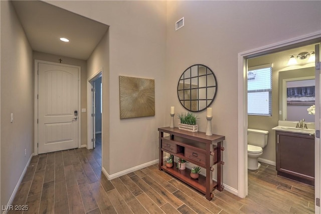 corridor with visible vents, baseboards, and wood finished floors