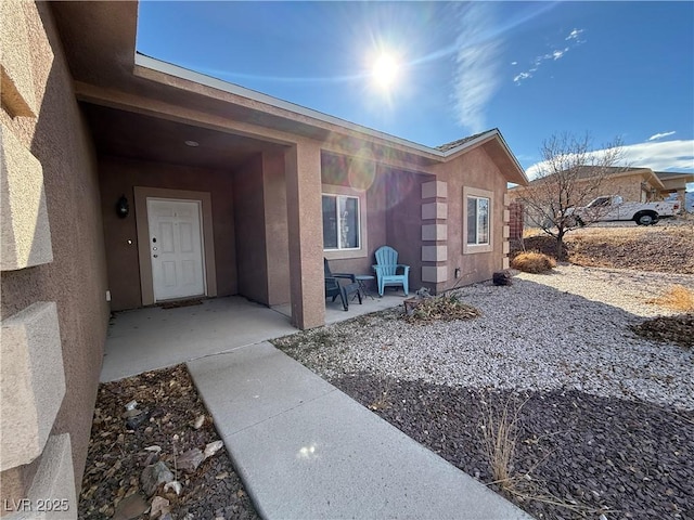 view of exterior entry with a patio area and stucco siding