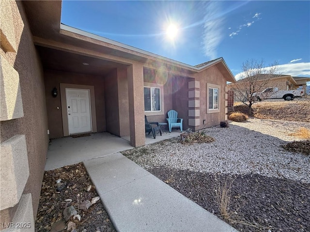 view of exterior entry with a patio area and stucco siding