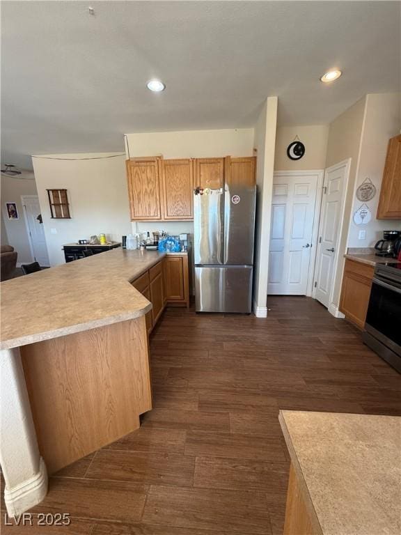 kitchen featuring recessed lighting, light countertops, appliances with stainless steel finishes, dark wood-type flooring, and a peninsula