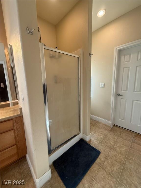 full bathroom featuring a stall shower, vanity, baseboards, and tile patterned floors