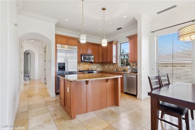 21 Via Visione Unit 201, Henderson, NV 89011 - kitchen featuring stainless steel appliances, a center island, backsplash, arched walkways, and ornamental molding