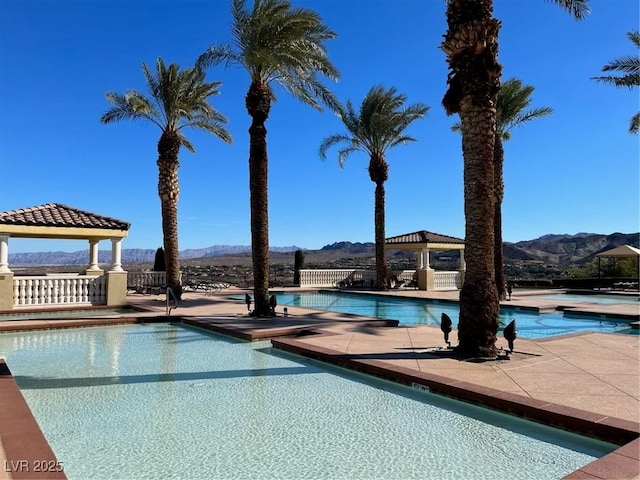 community pool featuring a patio area, a mountain view, and a gazebo