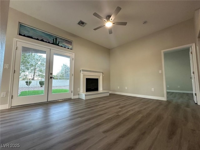 unfurnished living room featuring french doors, visible vents, a fireplace with raised hearth, dark wood-type flooring, and baseboards