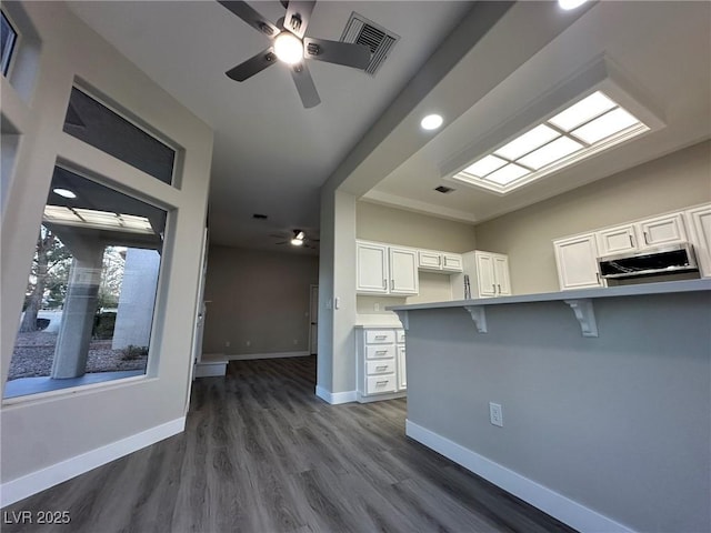 kitchen featuring a peninsula, white cabinetry, light countertops, and a kitchen breakfast bar