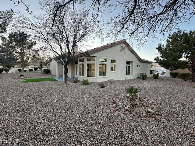 rear view of property with a tile roof, a patio area, cooling unit, and stucco siding