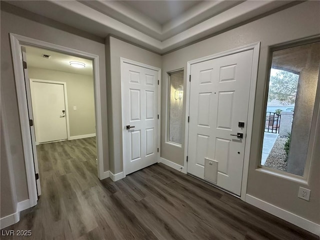 foyer entrance featuring dark wood-style flooring, visible vents, and baseboards