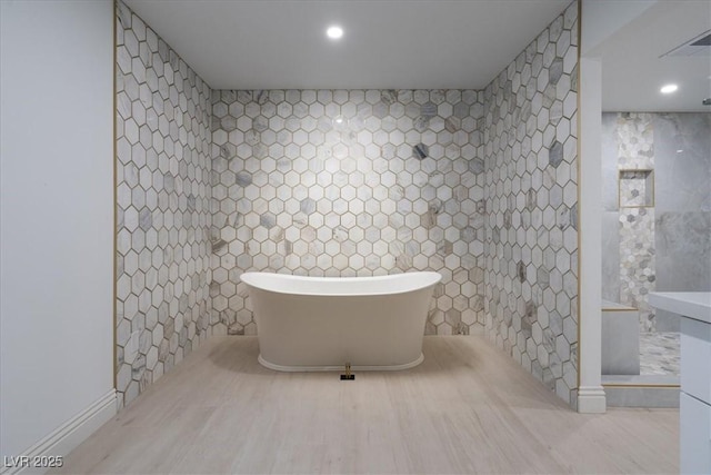 full bath featuring visible vents, a tile shower, a freestanding tub, tile walls, and recessed lighting