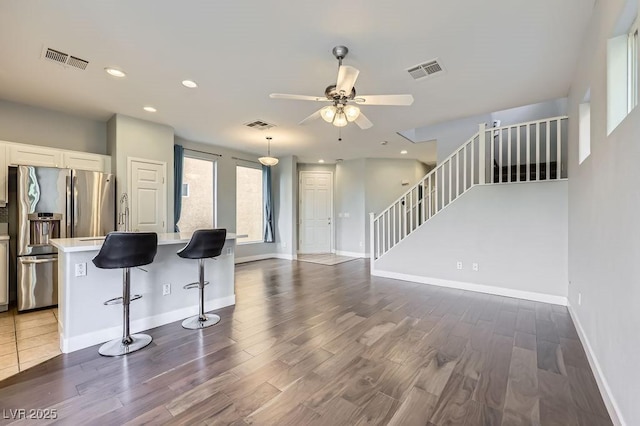 kitchen featuring a breakfast bar, light countertops, visible vents, white cabinetry, and stainless steel fridge with ice dispenser