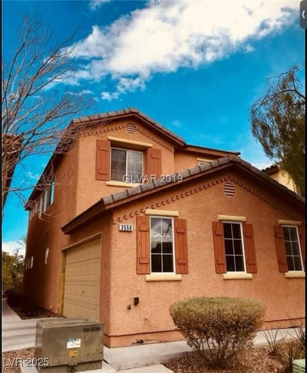 view of home's exterior with an attached garage, a tiled roof, and stucco siding