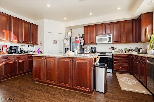 kitchen featuring recessed lighting, stainless steel appliances, a kitchen island, and dark wood-style flooring