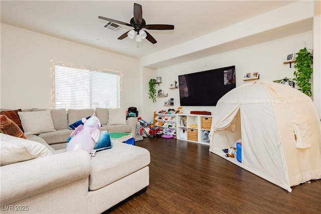 living area with visible vents, a ceiling fan, and wood finished floors