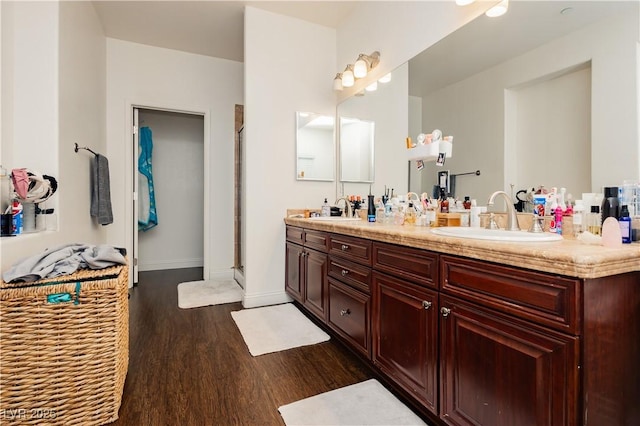 full bathroom with double vanity, a shower stall, wood finished floors, and a sink