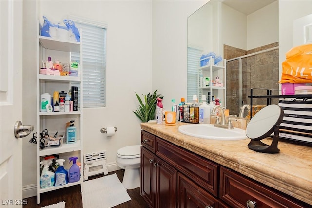 bathroom with a shower stall, toilet, vanity, and baseboards