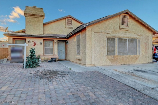 back of house with a patio area, a chimney, and stucco siding