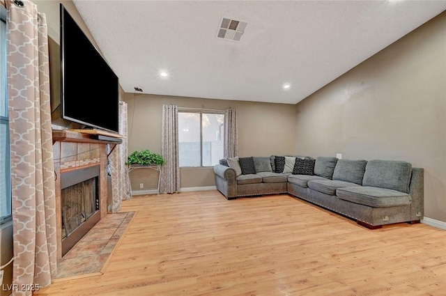 living area featuring light wood finished floors, recessed lighting, visible vents, a tiled fireplace, and baseboards