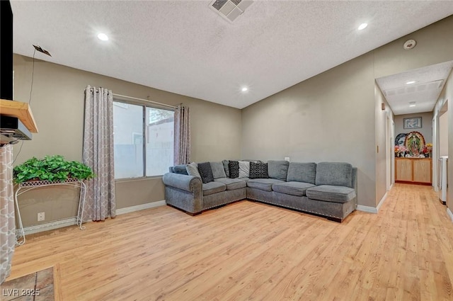 living room with light wood-style flooring, visible vents, and a textured ceiling