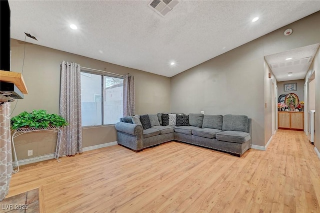 living area with a textured ceiling, light wood-style flooring, and visible vents