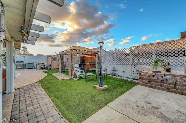 view of yard with an outbuilding, a patio area, fence, and a gazebo