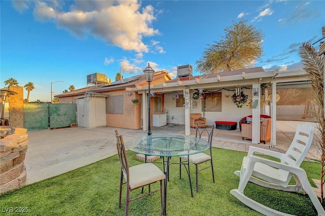 rear view of house featuring a yard, roof mounted solar panels, a patio area, central AC, and fence