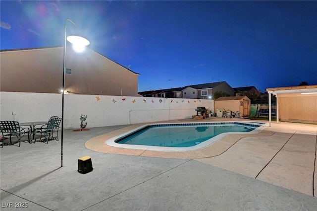 view of swimming pool featuring a storage shed, a patio, an outdoor structure, and a fenced backyard