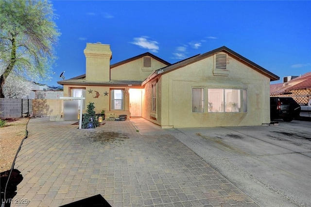 rear view of property with a patio area, fence, a chimney, and stucco siding