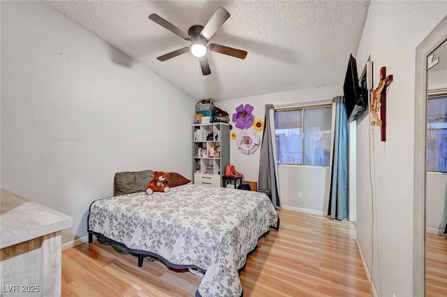 bedroom featuring light wood-style floors, baseboards, vaulted ceiling, and a textured ceiling