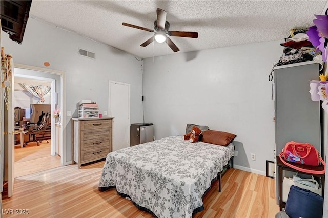 bedroom featuring visible vents, baseboards, a ceiling fan, a textured ceiling, and light wood-style floors