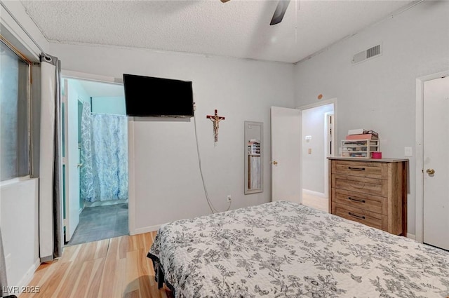 bedroom with a textured ceiling, ceiling fan, light wood finished floors, and visible vents