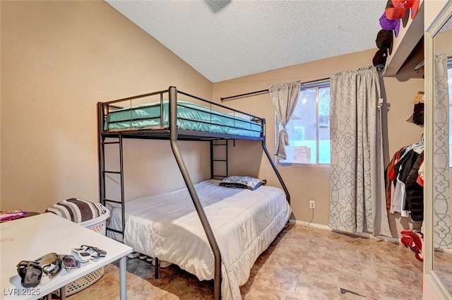 bedroom featuring lofted ceiling, a textured ceiling, and baseboards