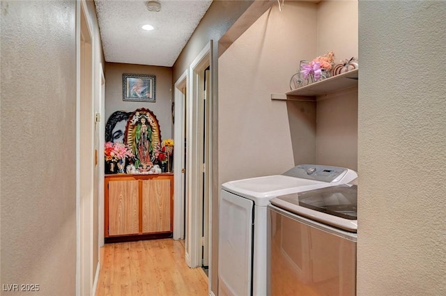 laundry room featuring a textured wall, light wood-style floors, laundry area, and washer and dryer