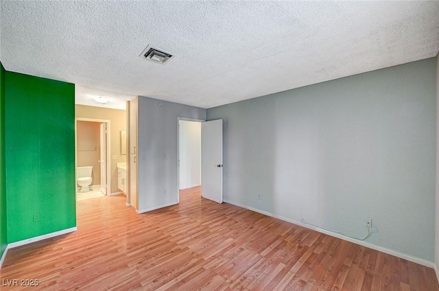 empty room with light wood-style flooring, visible vents, and baseboards