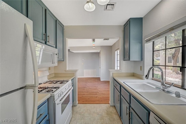 kitchen featuring light countertops, white appliances, visible vents, and a sink