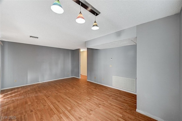 spare room with baseboards, visible vents, and wood finished floors