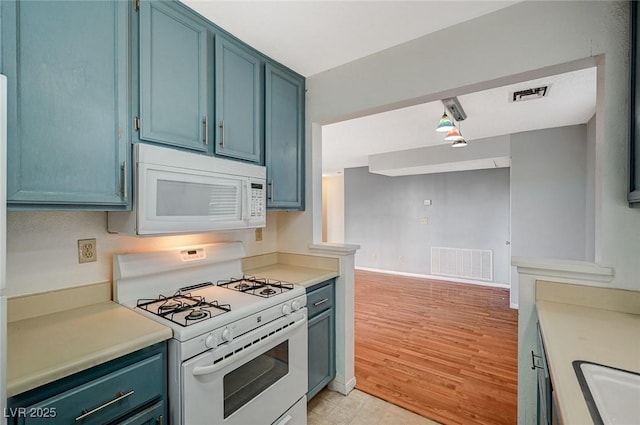 kitchen with blue cabinets, white appliances, visible vents, and light countertops