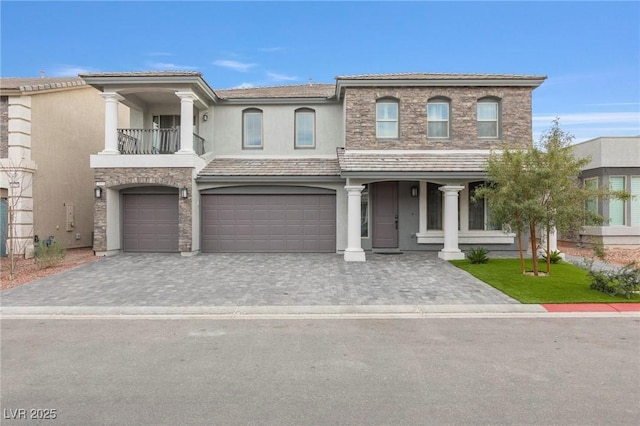 view of front of property with a balcony, a garage, a tiled roof, decorative driveway, and stucco siding